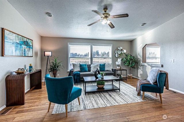 living room with ceiling fan, light hardwood / wood-style floors, and a textured ceiling