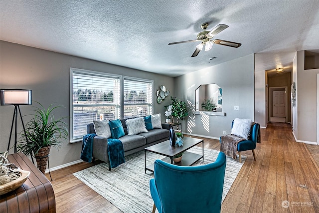 living room with hardwood / wood-style flooring, ceiling fan, and a textured ceiling