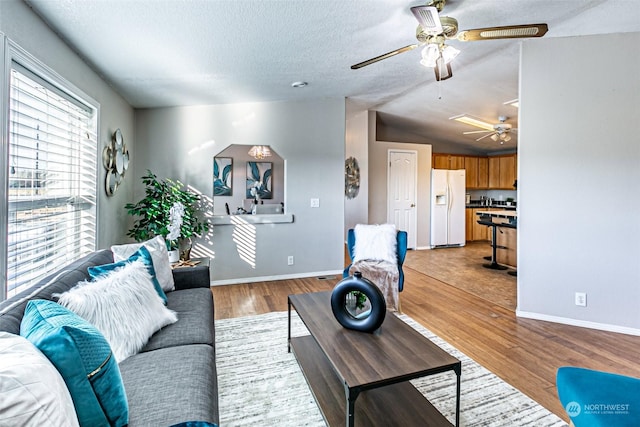 living room with lofted ceiling, light wood-type flooring, and a textured ceiling