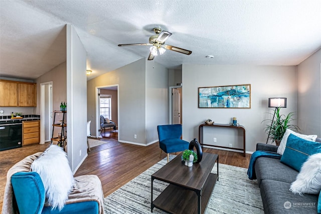 living room featuring a textured ceiling, ceiling fan, dark wood-type flooring, and vaulted ceiling