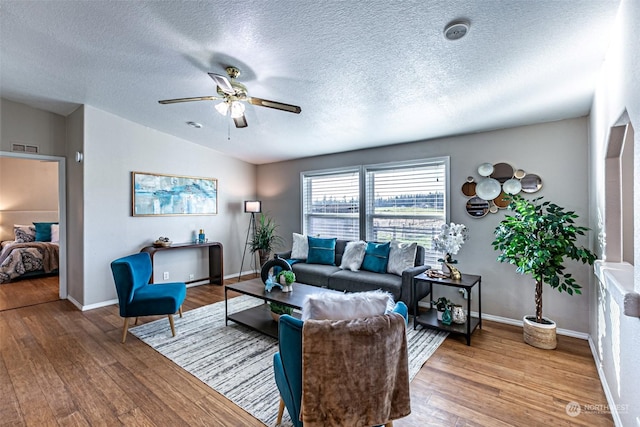 living room featuring ceiling fan, wood-type flooring, and a textured ceiling