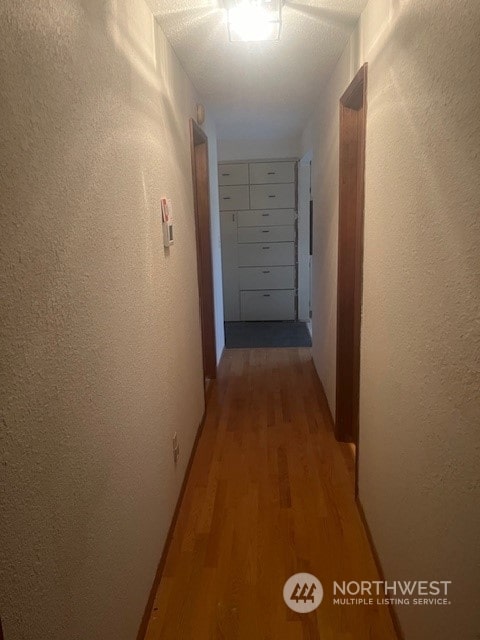 hall featuring a textured ceiling and hardwood / wood-style flooring