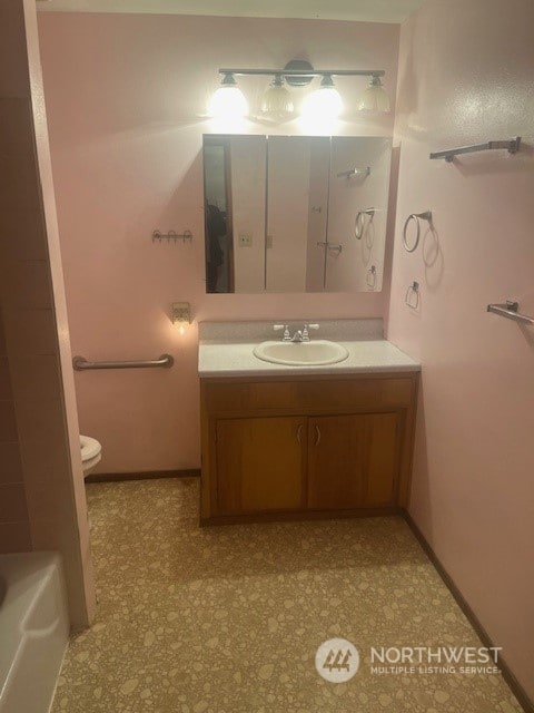 bathroom with a tub, vanity, and toilet