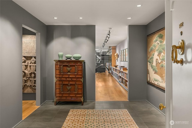 corridor with rail lighting and dark tile patterned floors