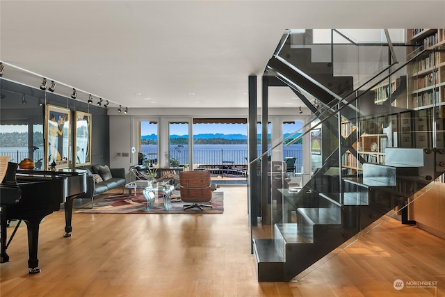 interior space with a water and mountain view, hardwood / wood-style floors, and track lighting