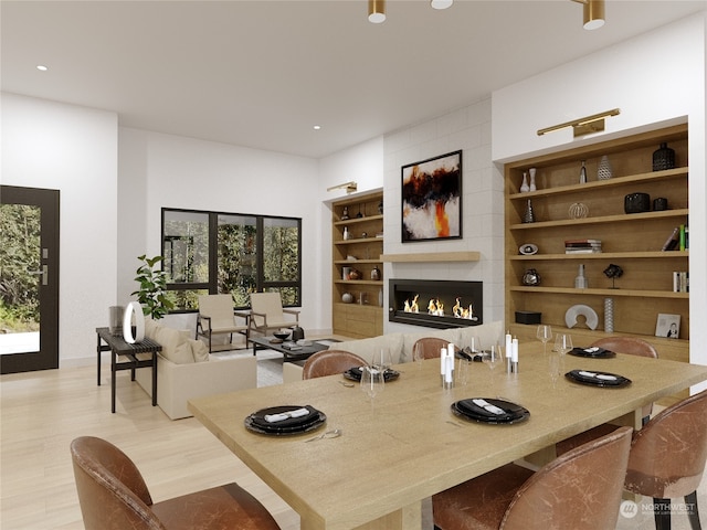 dining area featuring a large fireplace, light hardwood / wood-style floors, and a wealth of natural light