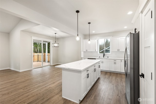 kitchen featuring wood-type flooring, a center island, white cabinetry, hanging light fixtures, and stainless steel refrigerator