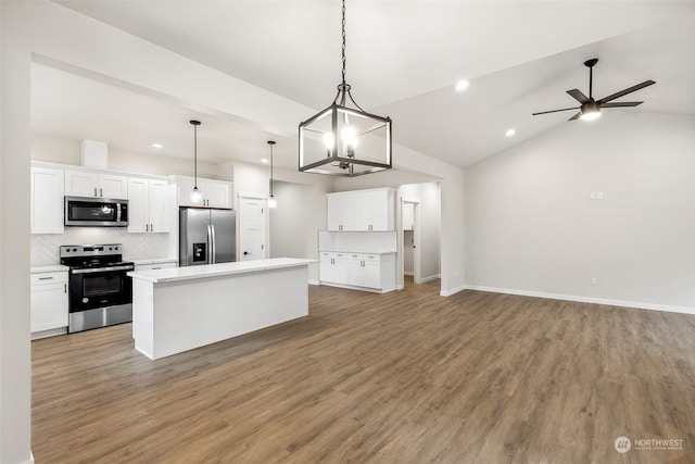 kitchen with stainless steel appliances, vaulted ceiling, a kitchen island, pendant lighting, and white cabinetry