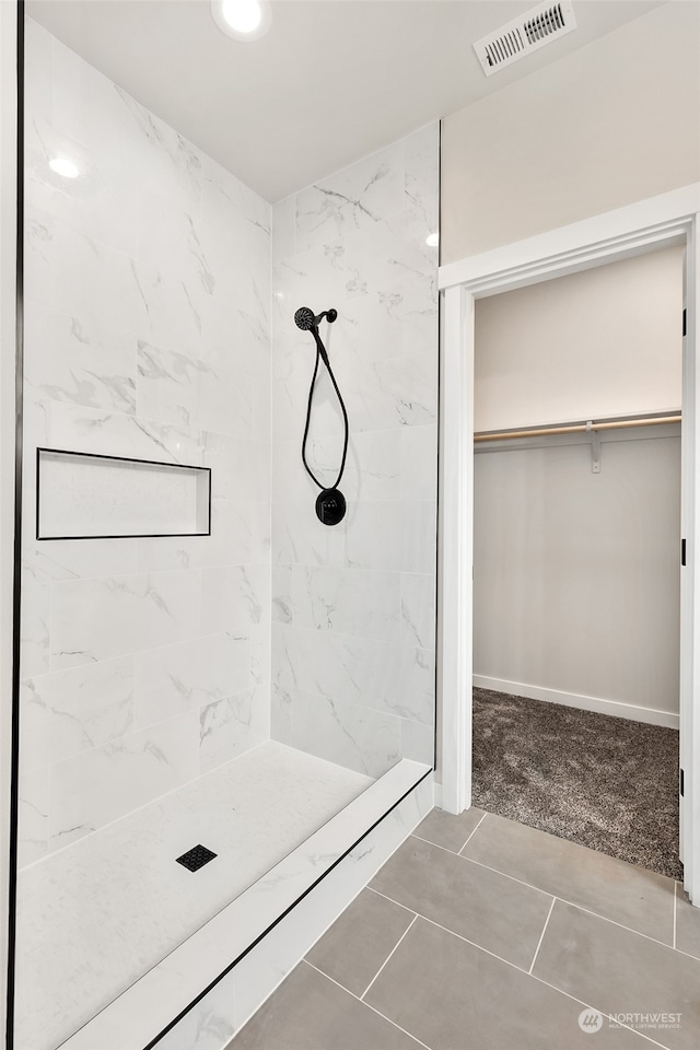 bathroom featuring tile patterned floors and a tile shower