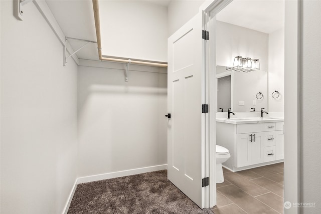 walk in closet featuring dark colored carpet and sink