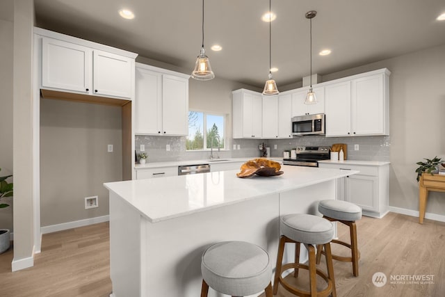 kitchen with a kitchen island, white cabinets, and appliances with stainless steel finishes