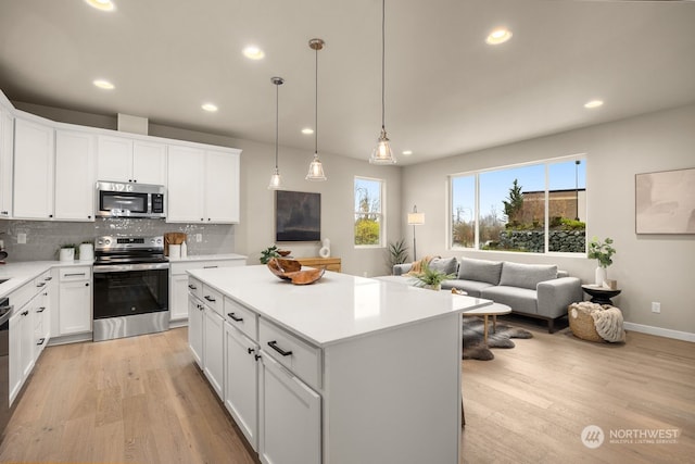 kitchen with decorative backsplash, light wood-type flooring, stainless steel appliances, decorative light fixtures, and white cabinetry