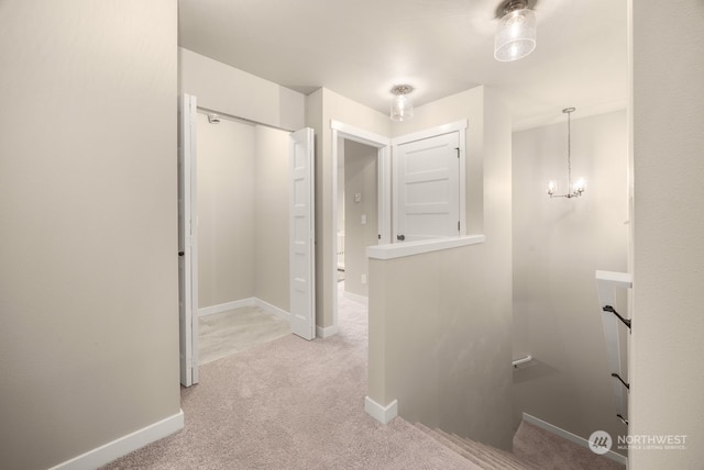 corridor with light colored carpet and an inviting chandelier