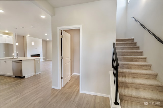 stairs with hardwood / wood-style floors, a large fireplace, and sink