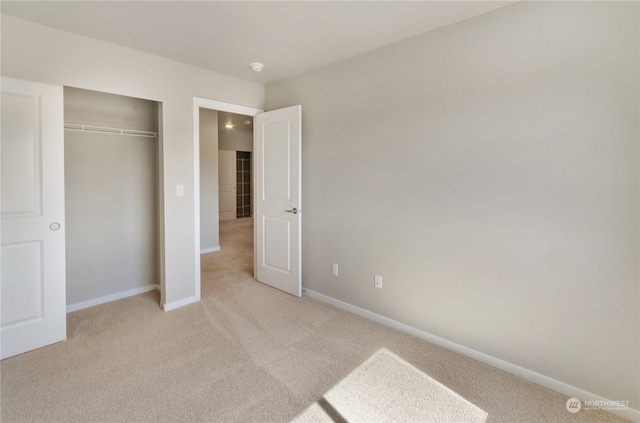 unfurnished bedroom with light carpet and a closet