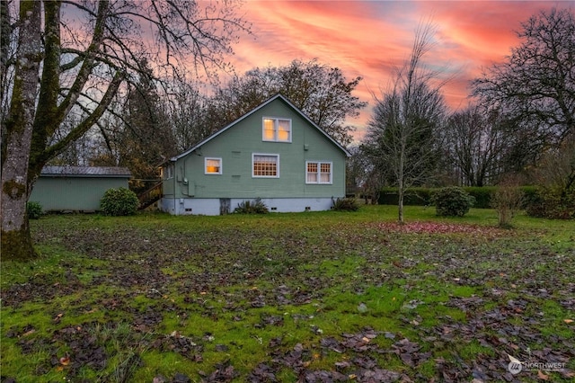 property exterior at dusk featuring a lawn