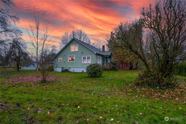 property exterior at dusk featuring a yard