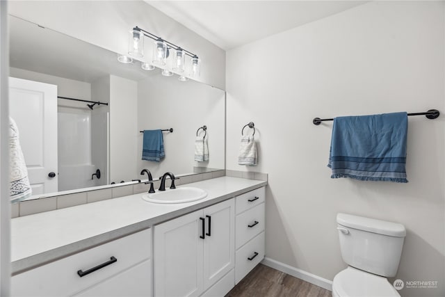 bathroom with vanity, hardwood / wood-style flooring, toilet, and walk in shower