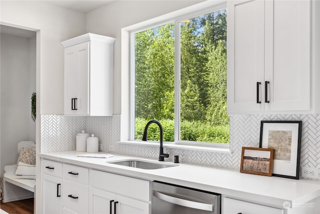 kitchen with tasteful backsplash, sink, stainless steel dishwasher, and white cabinets