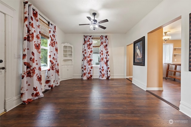 unfurnished room with ceiling fan with notable chandelier and dark hardwood / wood-style floors