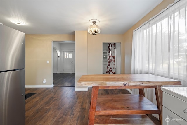 dining room with dark hardwood / wood-style floors, a healthy amount of sunlight, and a notable chandelier