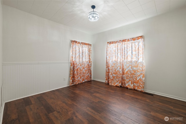 empty room featuring wooden walls and dark wood-type flooring