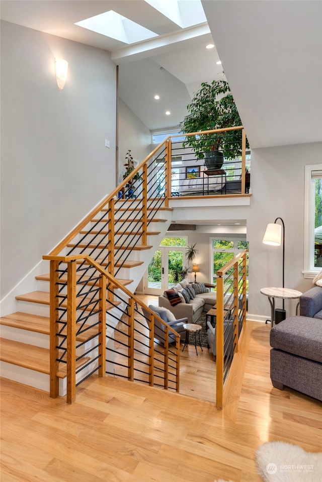 stairs featuring lofted ceiling with skylight and wood-type flooring