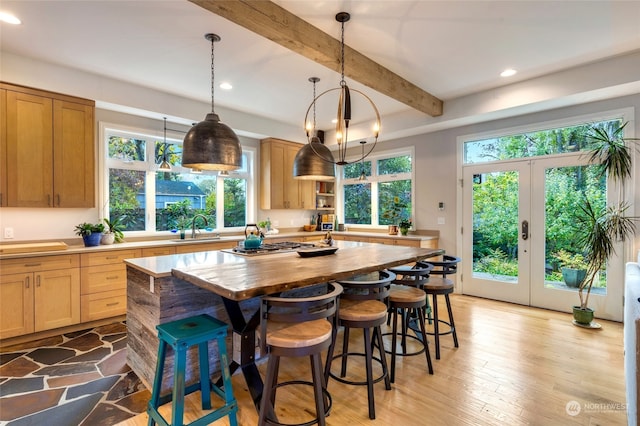 kitchen with plenty of natural light, beam ceiling, sink, and light hardwood / wood-style flooring