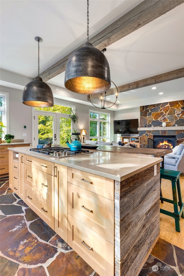 kitchen featuring light brown cabinetry, beamed ceiling, dark wood-type flooring, and stainless steel gas cooktop