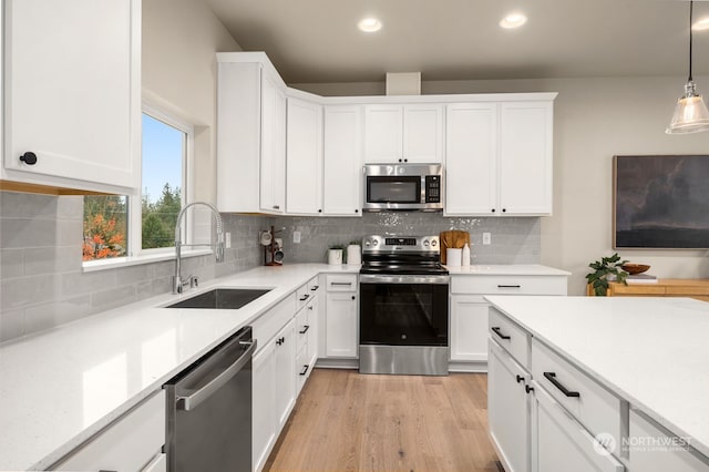 kitchen with decorative light fixtures, sink, white cabinetry, and stainless steel appliances