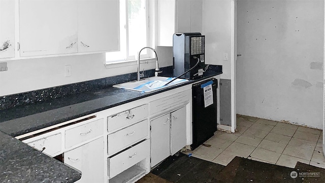 kitchen featuring sink, white cabinets, dark tile patterned flooring, and black dishwasher