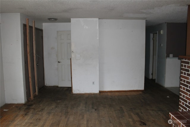 spare room with a textured ceiling and dark wood-type flooring