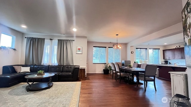 dining room with a wealth of natural light, dark wood-type flooring, and a notable chandelier