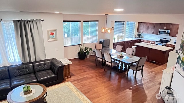 living room featuring hardwood / wood-style flooring, vaulted ceiling, sink, and an inviting chandelier