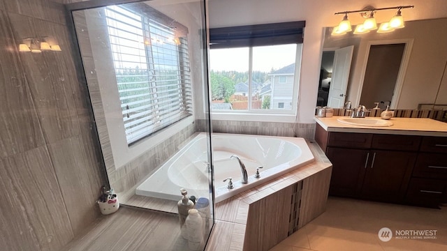 bathroom featuring tile patterned floors, vanity, a healthy amount of sunlight, and tiled tub