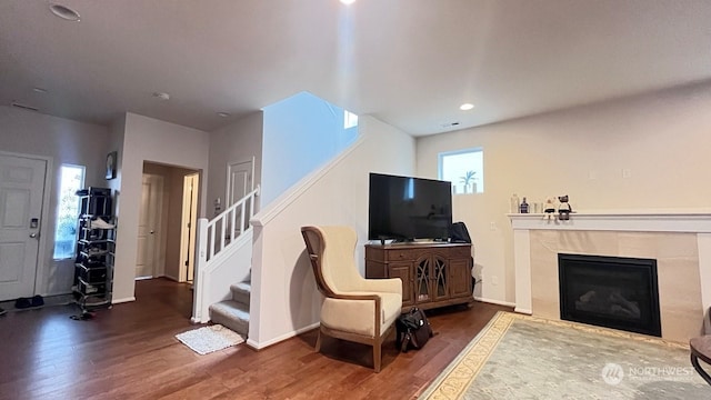 living room featuring a tile fireplace and dark wood-type flooring