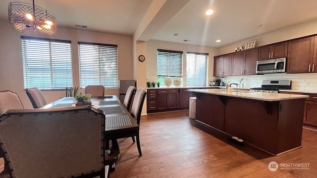 kitchen with pendant lighting, a healthy amount of sunlight, stainless steel appliances, and a kitchen island with sink