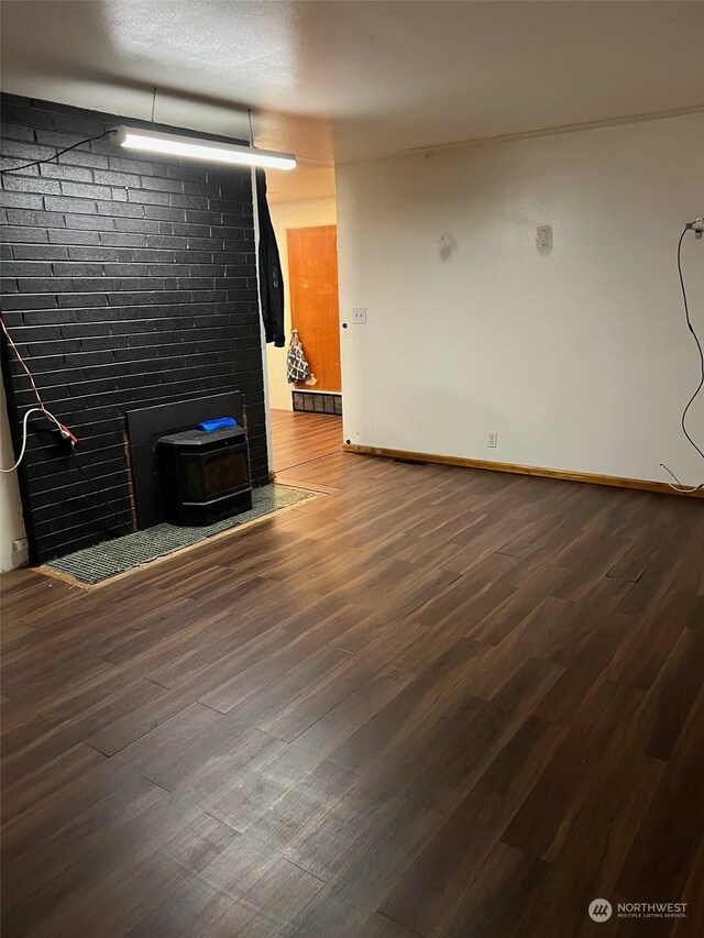 unfurnished living room with a wood stove, hardwood / wood-style floors, and a textured ceiling