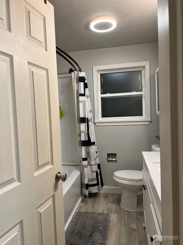 full bathroom with shower / bath combo with shower curtain, vanity, wood-type flooring, and toilet