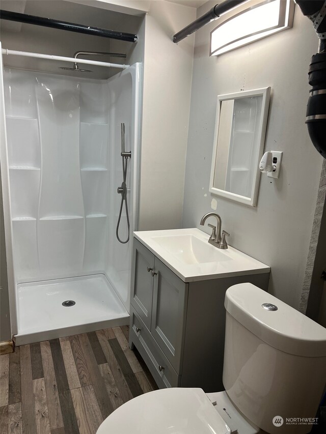 bathroom featuring a shower, hardwood / wood-style floors, vanity, and toilet