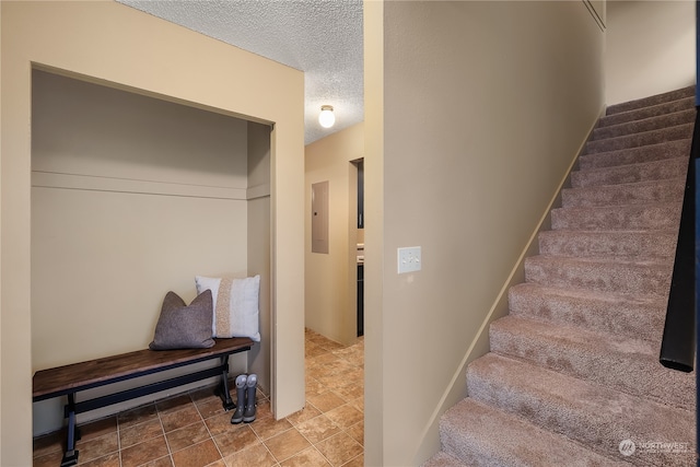 stairway with a textured ceiling and electric panel