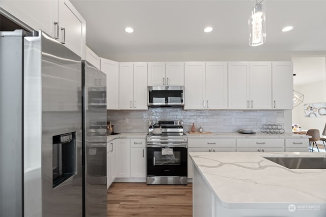 kitchen featuring decorative light fixtures, dark hardwood / wood-style flooring, white cabinetry, and appliances with stainless steel finishes