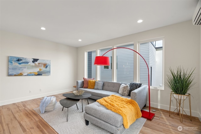 living room featuring light wood-type flooring and a wall unit AC