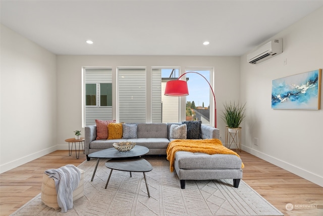 living room with a wall mounted air conditioner and light hardwood / wood-style flooring