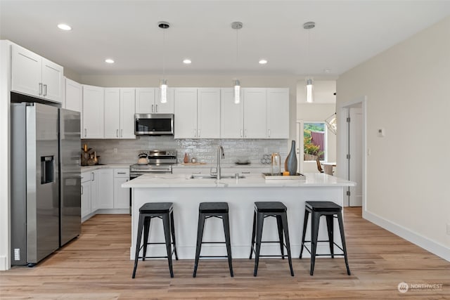 kitchen with white cabinets, pendant lighting, stainless steel appliances, and sink