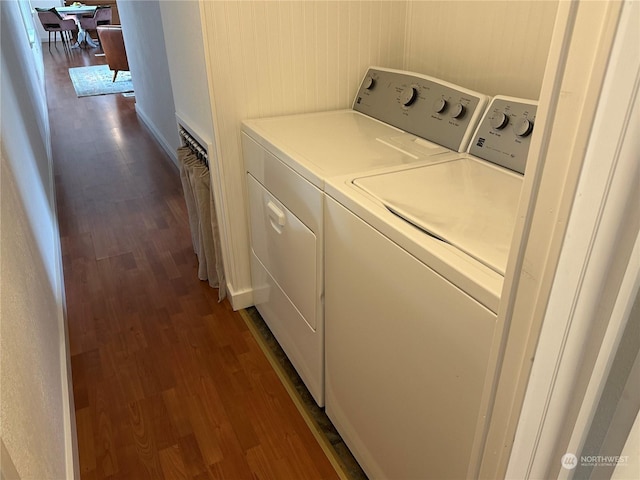 laundry room with separate washer and dryer, wooden walls, and dark hardwood / wood-style floors