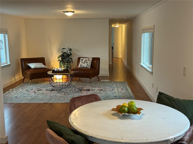 sitting room with ornamental molding and dark wood-type flooring