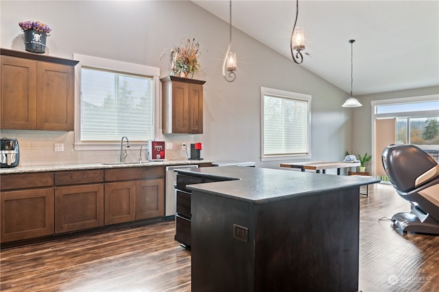 kitchen featuring decorative light fixtures, a center island, sink, and dark wood-type flooring