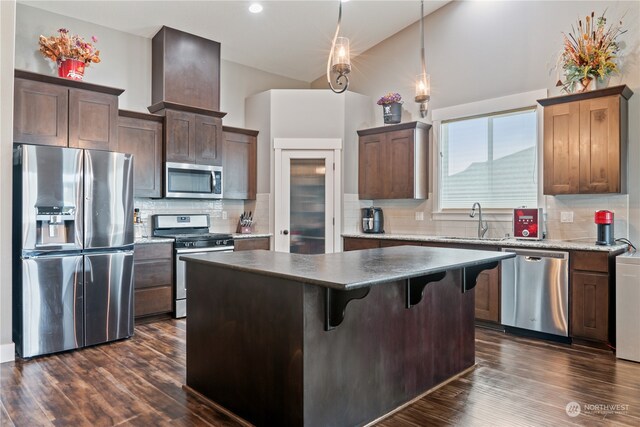 kitchen featuring dark hardwood / wood-style floors, a center island, decorative backsplash, and stainless steel appliances