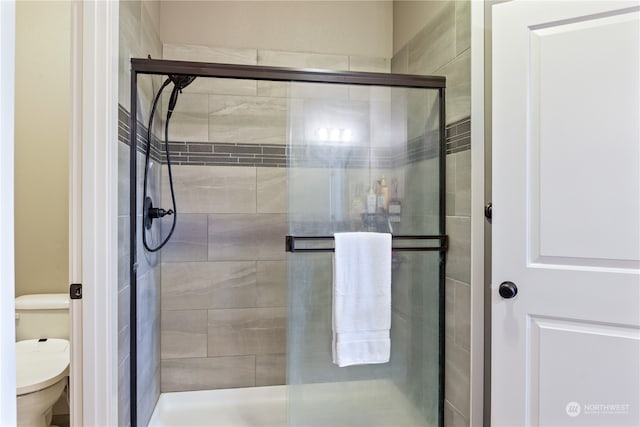 bathroom featuring toilet and a shower with door